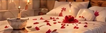 A bed scattered with rose petals beside candles